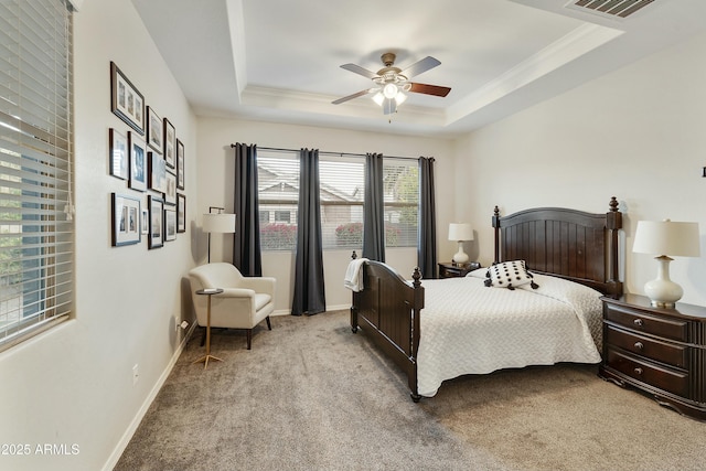 carpeted bedroom with a tray ceiling, multiple windows, ceiling fan, and ornamental molding