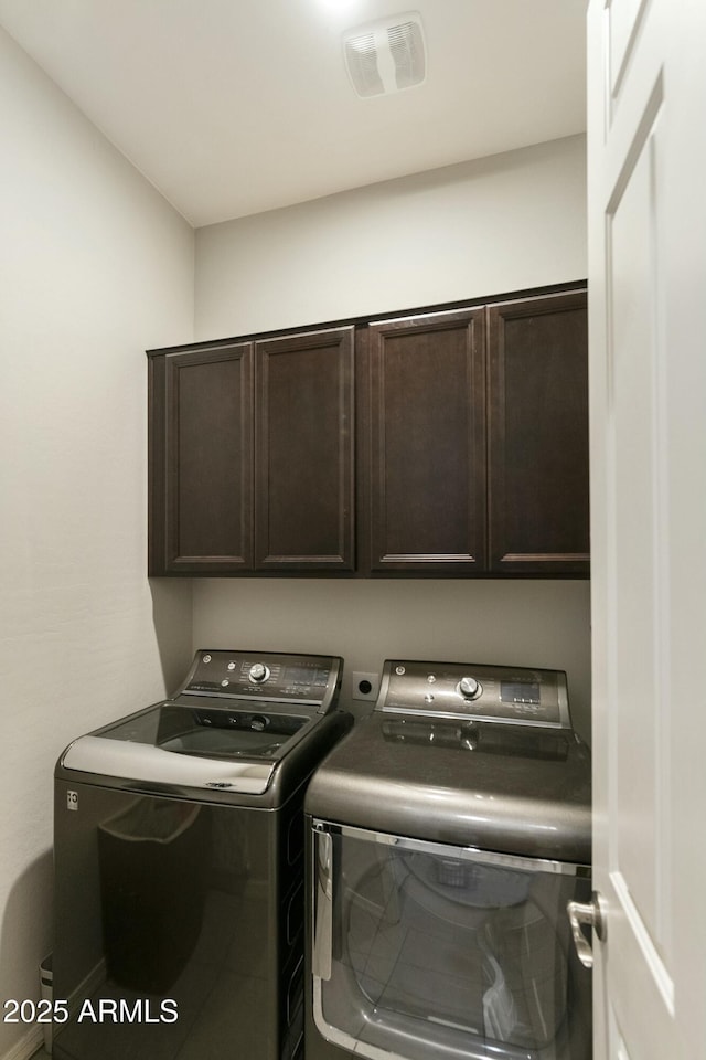 laundry room featuring washing machine and clothes dryer and cabinets