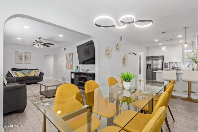 dining room featuring ceiling fan, sink, and light hardwood / wood-style flooring