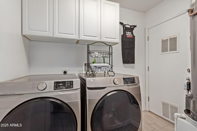 washroom with cabinets, washing machine and clothes dryer, and light wood-type flooring