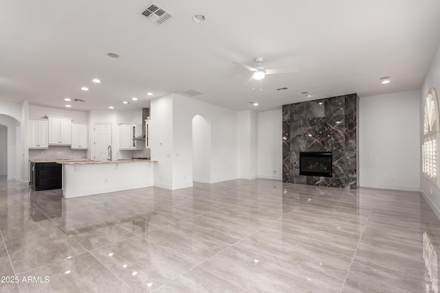 4711 E Buckboard Ct, Gilbert, AZ 85297 - unfurnished living room with arched walkways, ceiling fan, recessed lighting, a premium fireplace, and light tile patterned floors