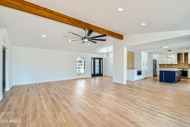 unfurnished living room with ceiling fan with notable chandelier, light hardwood / wood-style flooring, and lofted ceiling with beams