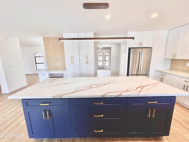 kitchen with white cabinetry, a center island, decorative light fixtures, and stainless steel refrigerator