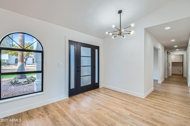 entrance foyer featuring vaulted ceiling, a notable chandelier, and light hardwood / wood-style floors