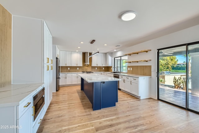 kitchen featuring stainless steel appliances, a kitchen island, pendant lighting, white cabinets, and light stone counters