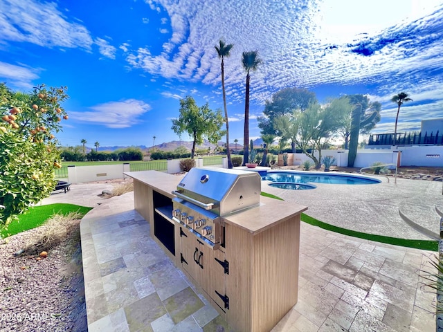 view of patio / terrace with exterior kitchen, a fenced in pool, and a grill