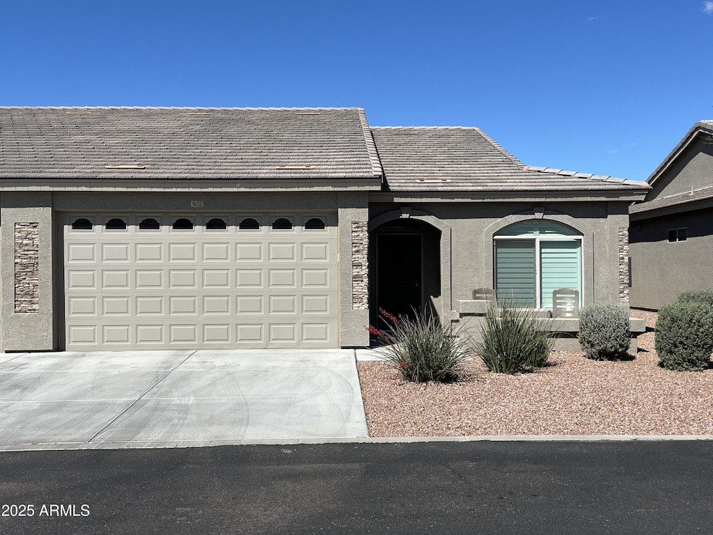 view of front of property with a garage, stone siding, concrete driveway, and stucco siding