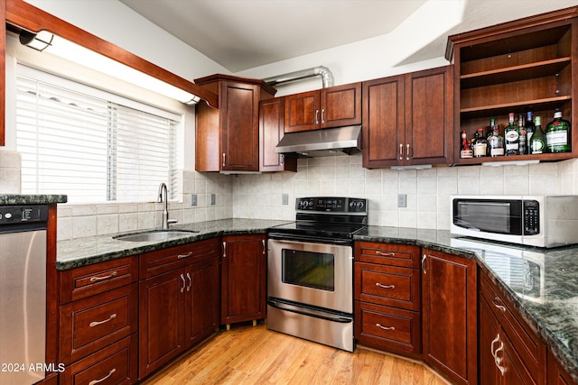 kitchen featuring stainless steel appliances, tasteful backsplash, sink, and dark stone counters