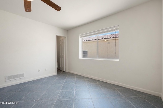 spare room with dark tile patterned flooring and ceiling fan