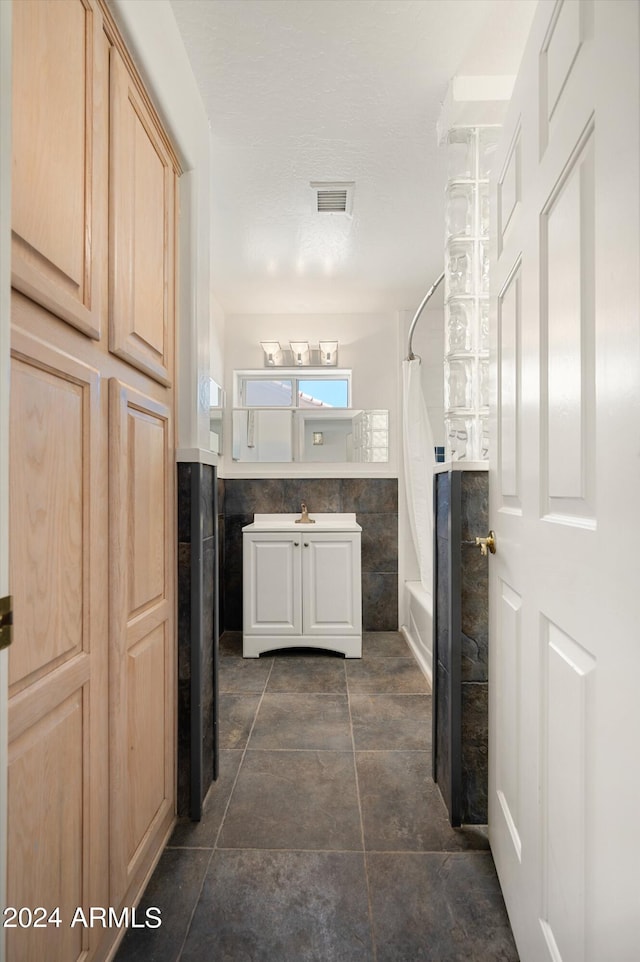 bathroom featuring vanity, tile walls, and shower / bath combination with curtain