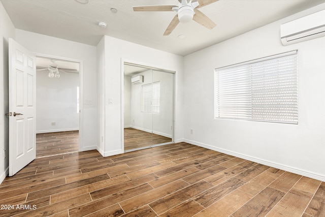 unfurnished bedroom featuring dark hardwood / wood-style floors, a wall unit AC, and a closet