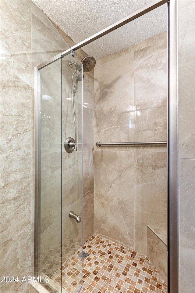 bathroom with a textured ceiling and a shower with shower door