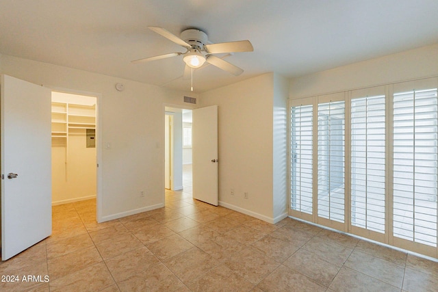 unfurnished bedroom featuring light tile patterned floors, ceiling fan, a walk in closet, and a closet