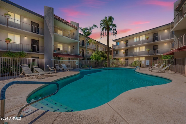 pool at dusk with a patio area