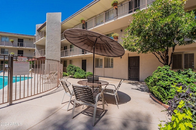 view of patio featuring a balcony and a community pool