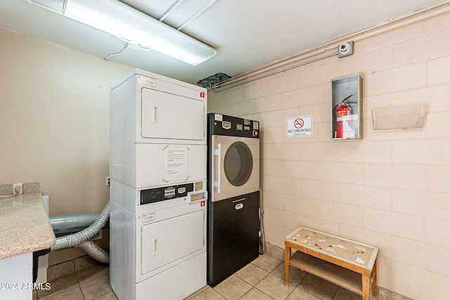 washroom featuring light tile patterned flooring and stacked washer / dryer