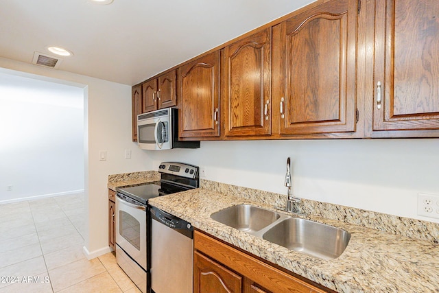 kitchen featuring appliances with stainless steel finishes, light tile patterned floors, sink, and light stone countertops