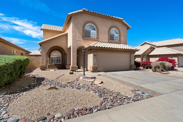 mediterranean / spanish home featuring stucco siding, a tiled roof, driveway, and a garage