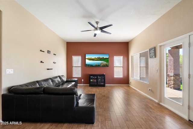 living area featuring baseboards, a ceiling fan, and wood finished floors