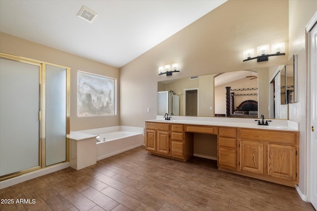 bathroom with a stall shower, a bath, double vanity, lofted ceiling, and visible vents
