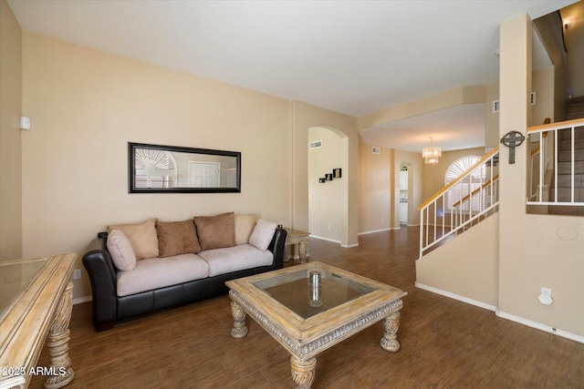 living area with arched walkways, baseboards, an inviting chandelier, wood finished floors, and stairs