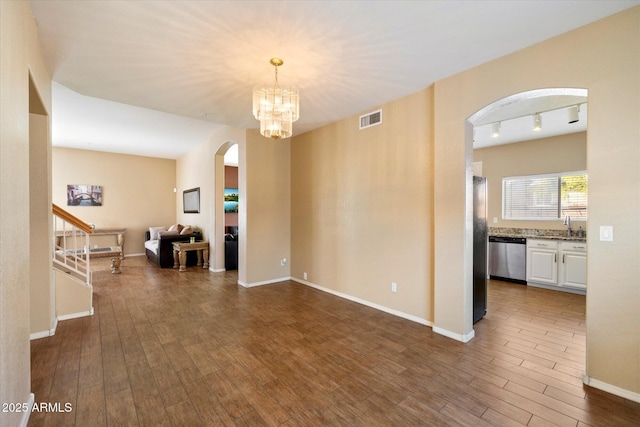 interior space featuring dark wood-style floors, visible vents, a sink, arched walkways, and a notable chandelier