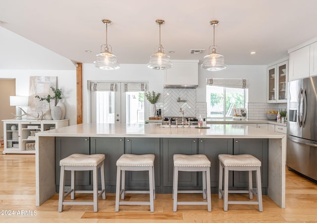 kitchen featuring appliances with stainless steel finishes, decorative light fixtures, white cabinets, and a spacious island