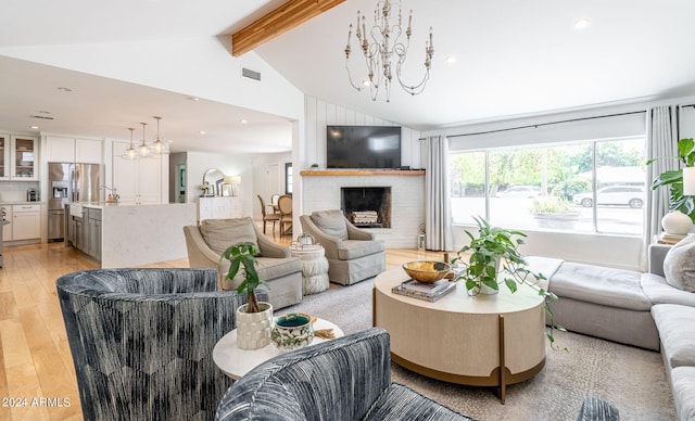 living room featuring an inviting chandelier, a fireplace, lofted ceiling with beams, and light wood-type flooring