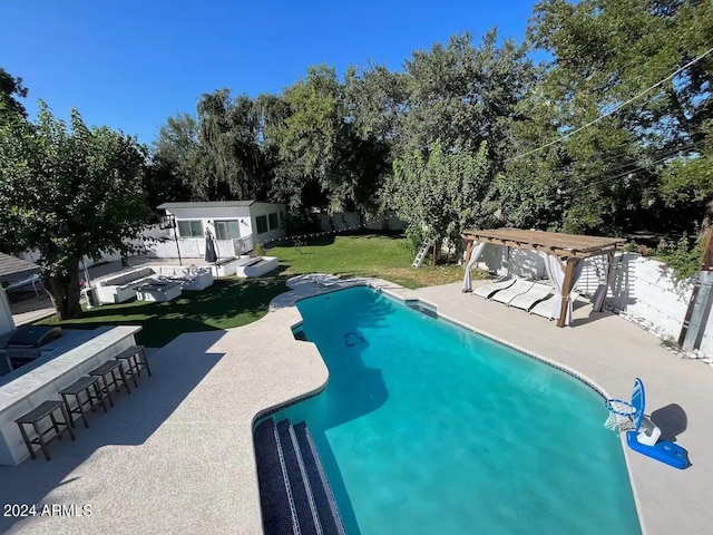 view of pool featuring a yard, a pergola, a patio area, an outdoor structure, and exterior bar