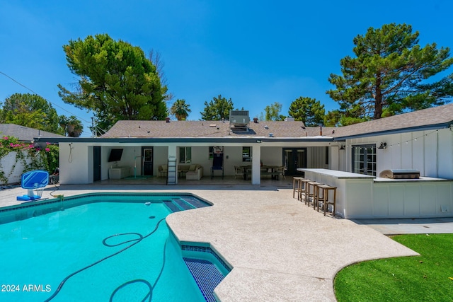 view of pool with a patio area, an outdoor kitchen, and exterior bar