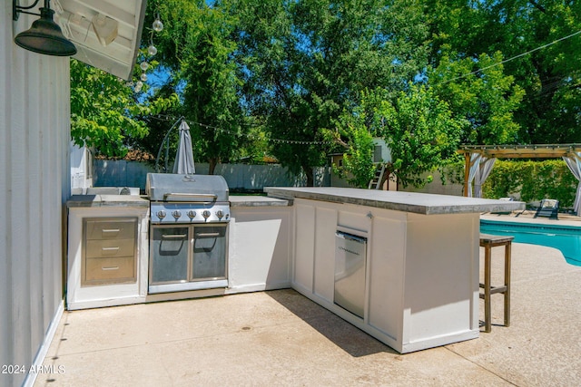 view of patio / terrace featuring a bar, a pergola, grilling area, and an outdoor kitchen