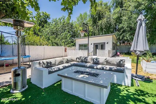 view of patio / terrace with an outbuilding, a trampoline, and an outdoor fire pit