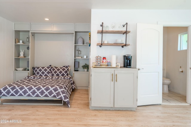 bedroom featuring ensuite bath and light wood-type flooring