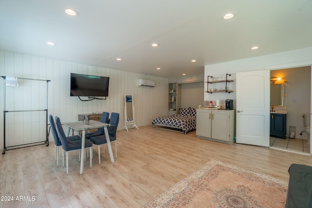 dining space with a wall mounted AC and light hardwood / wood-style floors