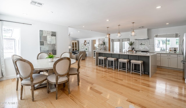 dining space with vaulted ceiling and light hardwood / wood-style floors