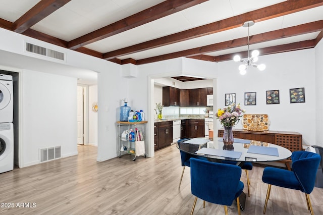 1101 E Bethany Home Rd Unit 1, Phoenix, AZ 85014 - dining area featuring stacked washing machine and dryer, beam ceiling, light wood-style flooring, a chandelier, and baseboards