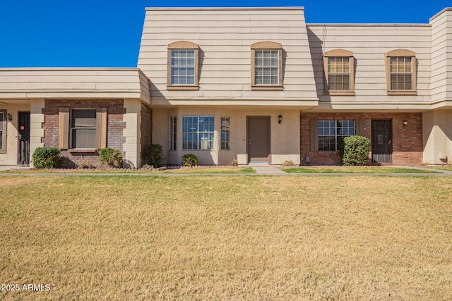 view of property featuring a front lawn and brick siding