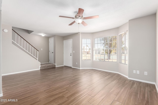 interior space featuring stairs, wood finished floors, a ceiling fan, and baseboards