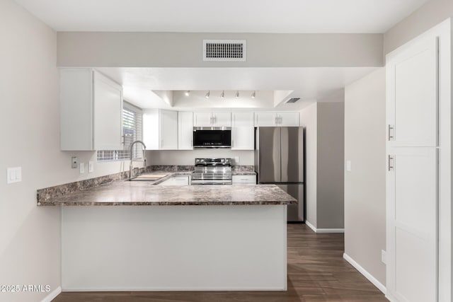 kitchen featuring stainless steel appliances, a peninsula, a sink, visible vents, and white cabinets