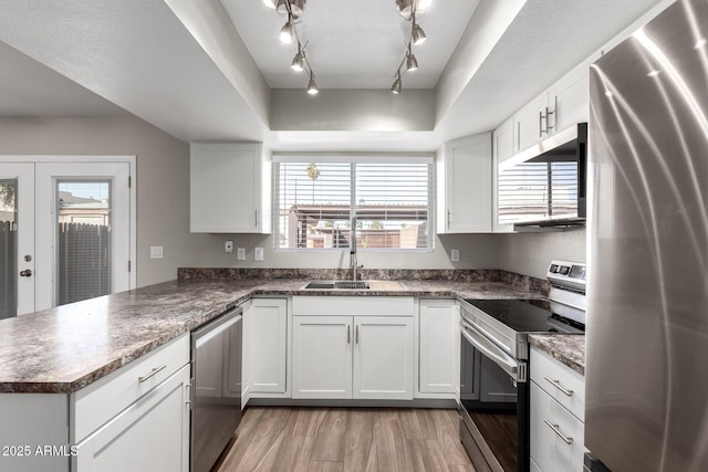 kitchen featuring stainless steel appliances, a sink, white cabinets, and light wood-style floors