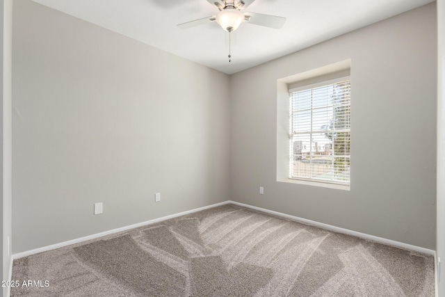 carpeted spare room with ceiling fan and baseboards