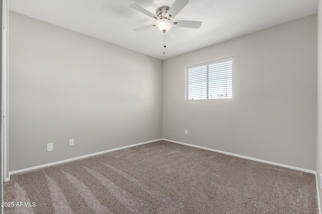 carpeted spare room with ceiling fan and baseboards