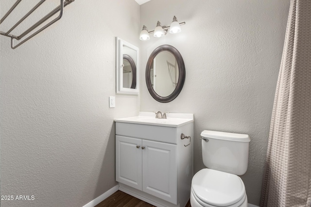 bathroom with a textured wall, vanity, toilet, and wood finished floors