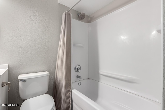 bathroom featuring shower / tub combo, a textured wall, and toilet