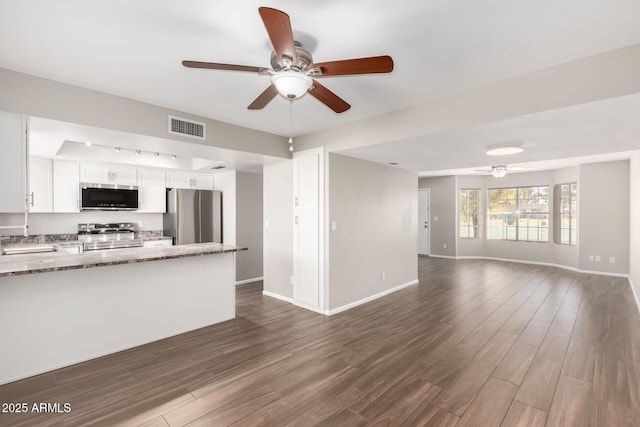 unfurnished living room with ceiling fan, a sink, visible vents, baseboards, and dark wood finished floors