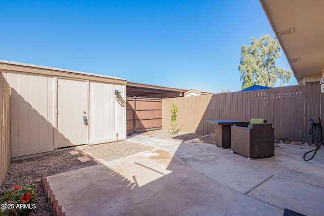 view of patio / terrace with an outbuilding, a fenced backyard, and visible vents