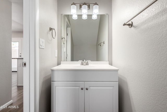 bathroom featuring vanity, wood finished floors, and a textured wall