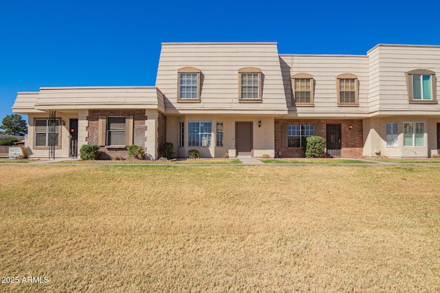 multi unit property with brick siding, a front lawn, and mansard roof