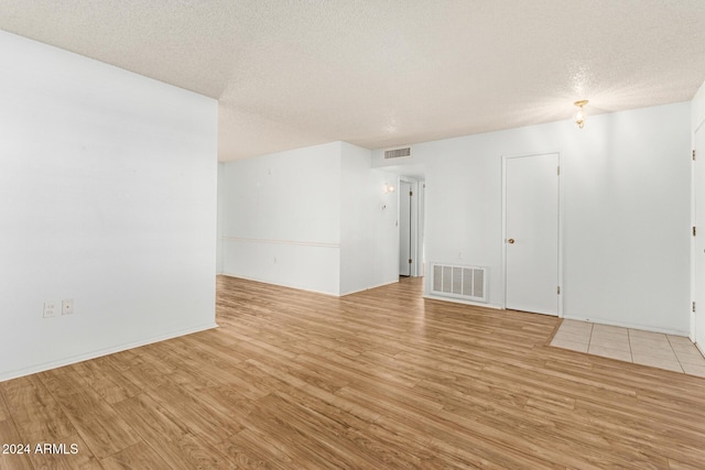 spare room with a textured ceiling and light hardwood / wood-style flooring