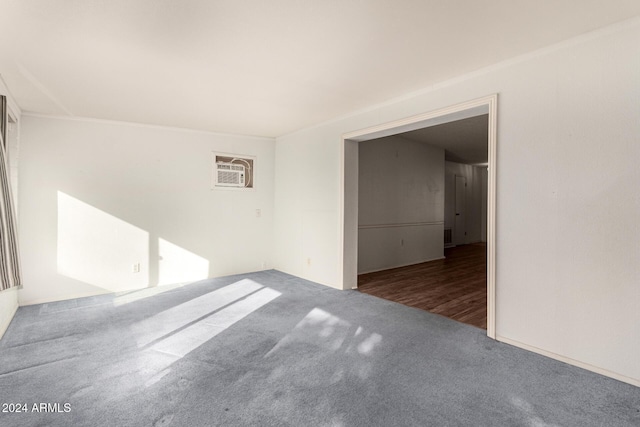 spare room featuring a wall mounted air conditioner and dark carpet